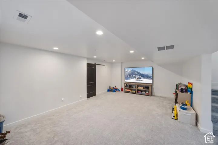 Carpeted home theater room featuring a barn door and recessed lighting