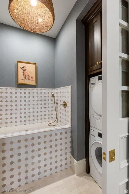 Full bathroom featuring tiled shower and stacked washer and clothes dryer