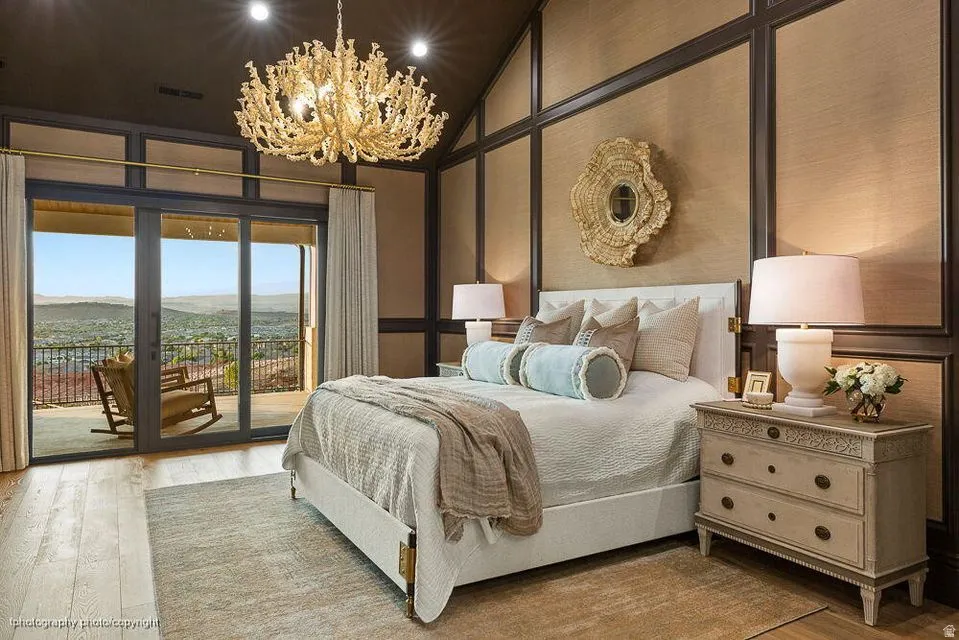 Bedroom with access to outside, a mountain view, wood finished floors, suspended lighting, and a decorative wall