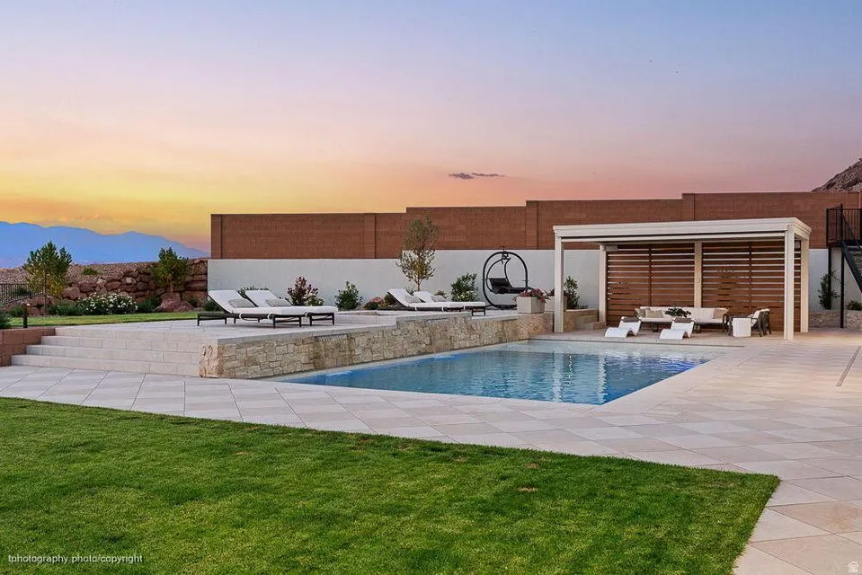Outdoor pool featuring outdoor lounge area, a fenced backyard, a patio area, a water slide, and a mountain view