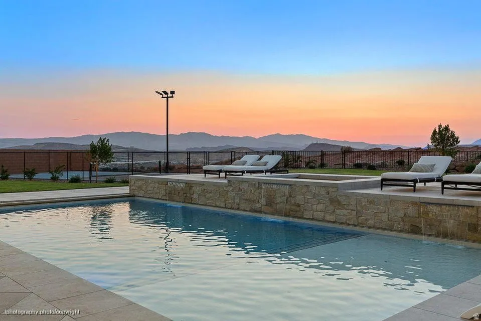 Pool at dusk with a patio area and a mountain view
