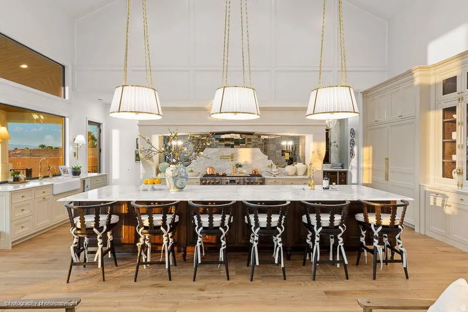 Kitchen featuring decorative light fixtures, light stone counters, a breakfast bar, vaulted ceiling, and a decorative wall