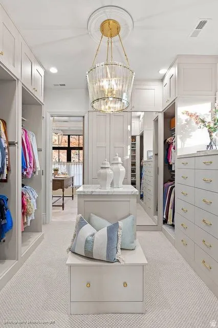 Walk in closet featuring light carpet and a chandelier