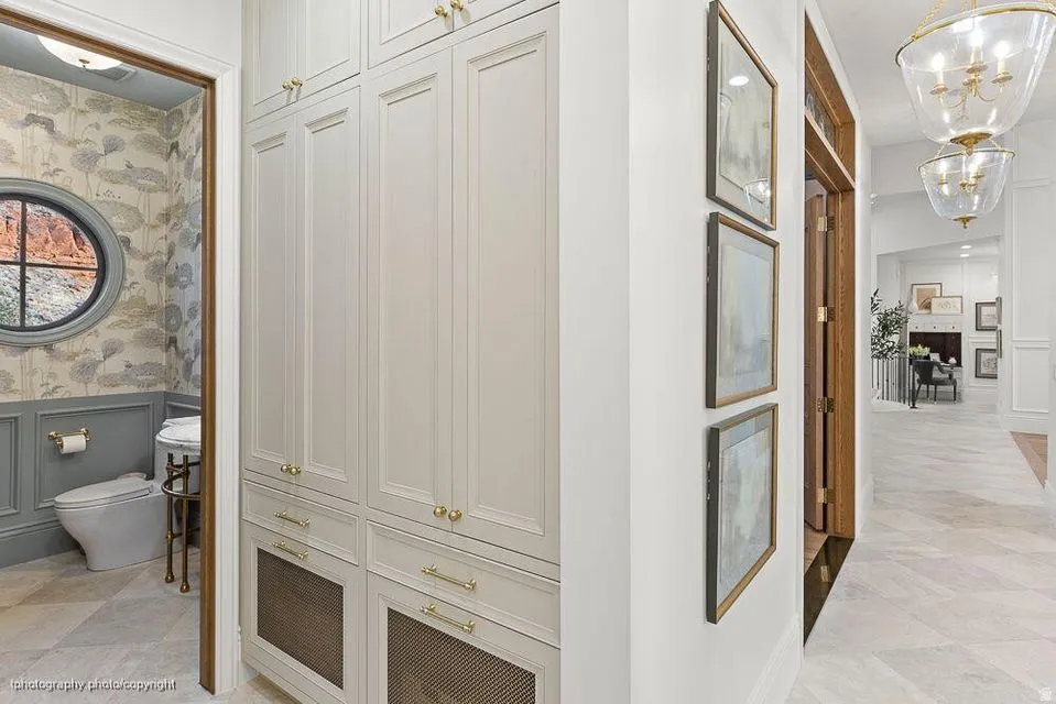 Hall featuring wallpapered walls, a chandelier, and a decorative wall