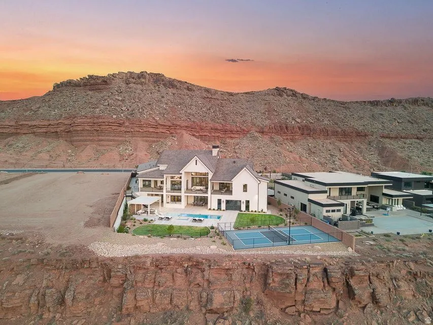 Back of house at dusk featuring a patio area, an outdoor pool, a mountain view, and a chimney