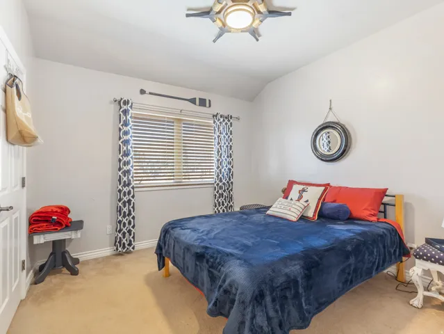 Carpeted bedroom featuring ceiling fan and lofted ceiling