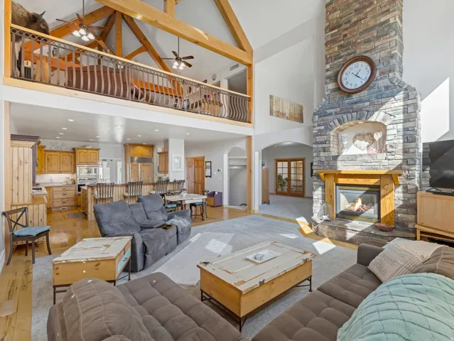 Living room featuring a large fireplace, light wood-style floors, arched walkways, ceiling fan, and vaulted ceiling