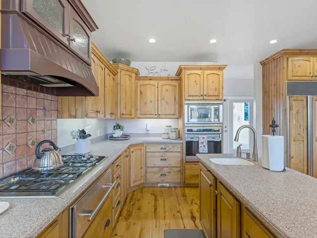 Kitchen featuring built in appliances, light stone countertops, a warming drawer, light wood-style flooring, and recessed lighting