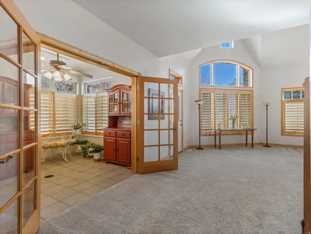 Unfurnished office with light colored carpet, a ceiling fan, lofted ceiling, french doors, and light tile patterned flooring