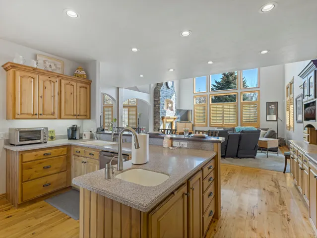 Kitchen with light wood-type flooring, a peninsula, open floor plan, recessed lighting, and light stone countertops