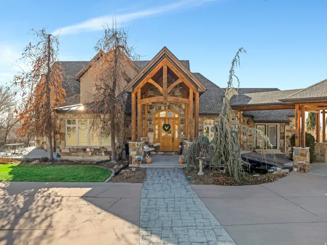 Stone facade with prominent wood beam accents, a covered entry, and a stamped concrete driveway