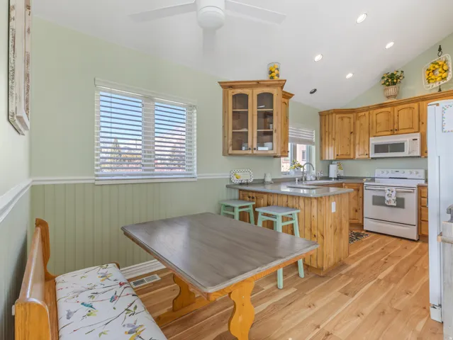 Kitchen with wainscoting, white appliances, a peninsula, glass fronted cabinets, and recessed lighting