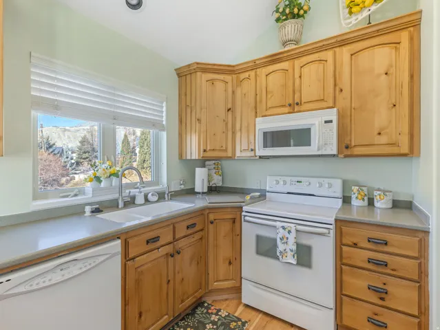 Kitchen featuring white appliances, light wood-style floors, and lofted ceiling