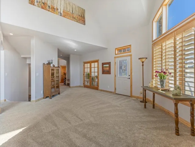 Carpeted entrance foyer featuring vaulted ceiling, arched walkways, recessed lighting, and french doors