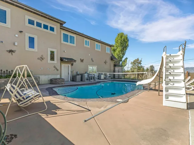 Expansive outdoor area featuring a swimming pool with a slide and volleyball net