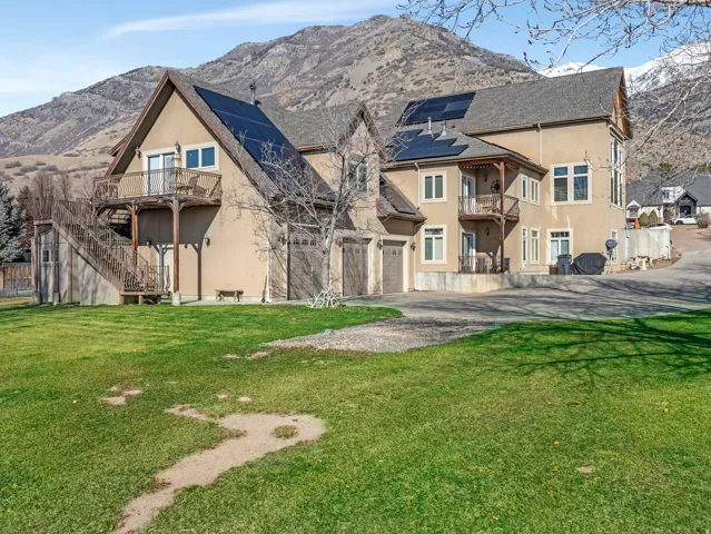 Stucco exterior with multiple balconies, attached garage, and solar panels