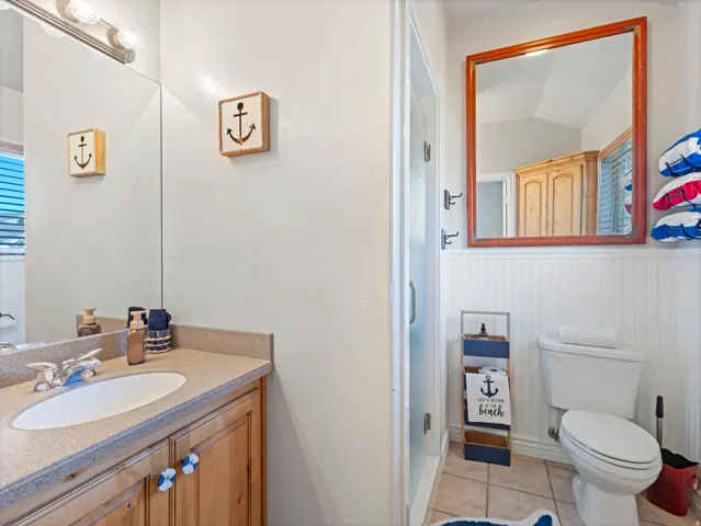 Bathroom with light tile patterned floors, vanity, a shower stall, and vaulted ceiling