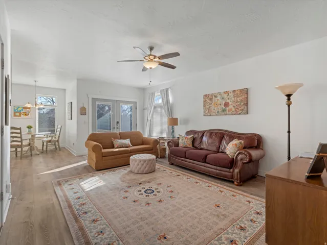 Living room with wood finished floors, ceiling fan, plenty of natural light, and french doors