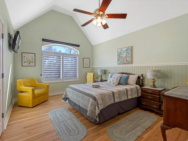 Bedroom featuring ceiling fan, wood finished floors, and a high ceiling