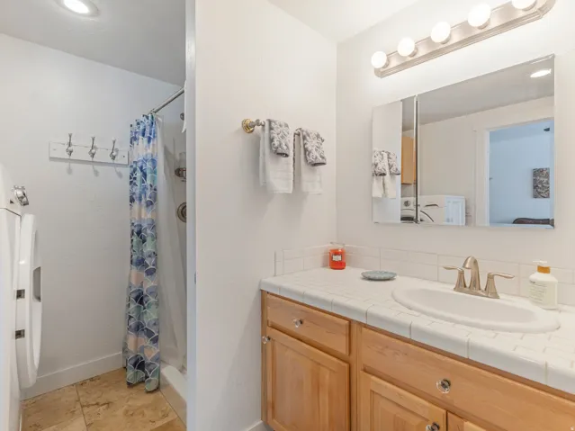 Bathroom featuring a shower with shower curtain, vanity, washer / dryer, and recessed lighting