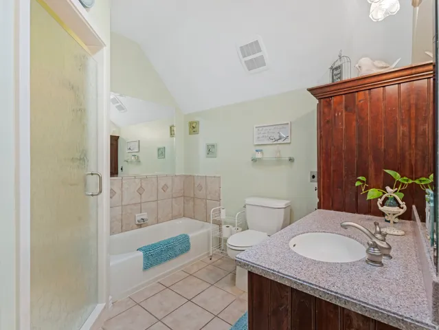 Full bathroom with a bath, a stall shower, vanity, light tile patterned flooring, and vaulted ceiling