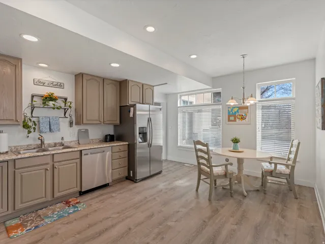 Kitchen with stainless steel appliances, light wood-style flooring, decorative light fixtures, and plenty of natural light