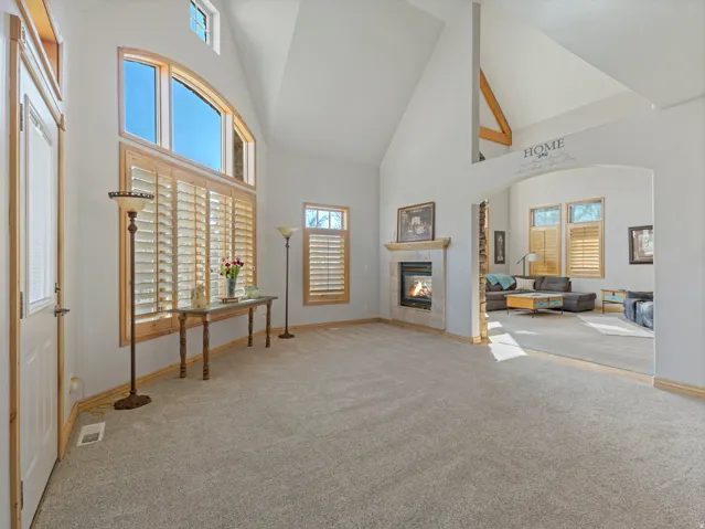 Unfurnished living room with light colored carpet, vaulted ceiling, and a fireplace