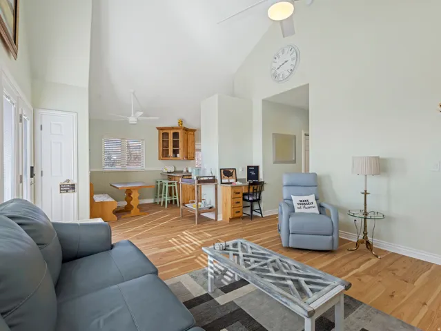 Living area featuring ceiling fan, light wood-style floors, and vaulted ceiling