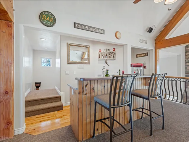 Indoor dry bar featuring light colored carpet, light wood-style floors, and ceiling fan