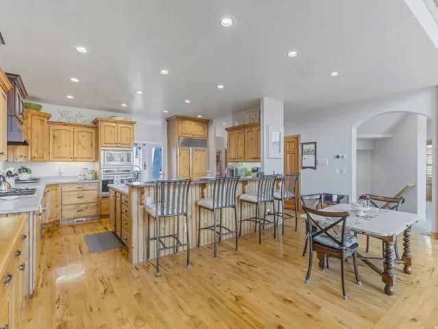 Kitchen featuring a breakfast bar area, arched walkways, light wood finished floors, built in appliances, and recessed lighting