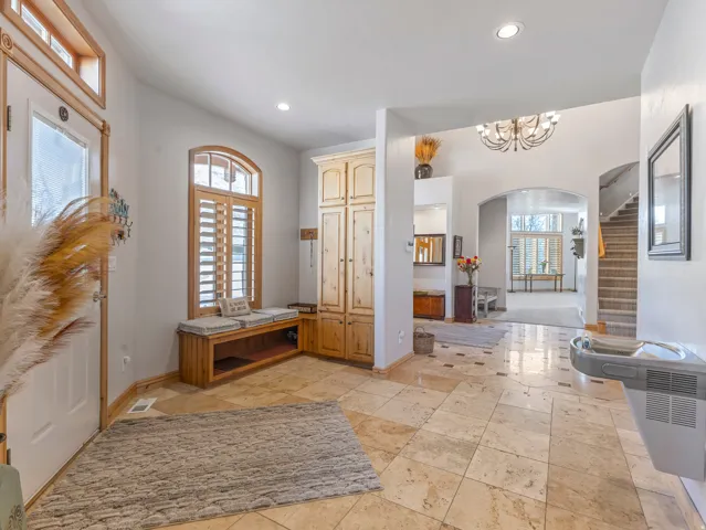 Entrance foyer with arched walkways, stone tile flooring, hanging lights, and plenty of natural light