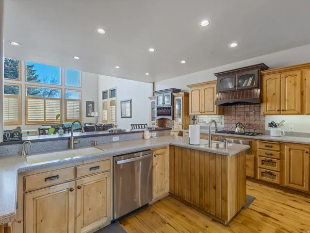 Kitchen featuring open floor plan, light wood-style flooring, stainless steel appliances, glass insert cabinets, and recessed lighting