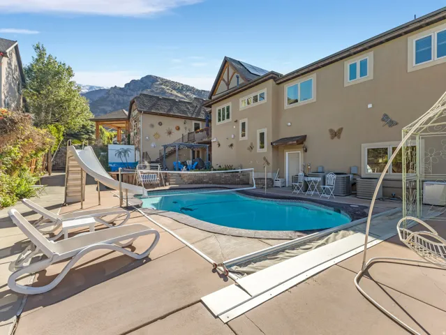Outdoor swimming pool with integrated slide and surrounding concrete patio