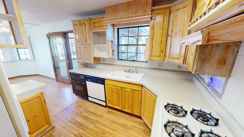 Kitchen with light wood finished floors, light countertops, white appliances, and healthy amount of natural light