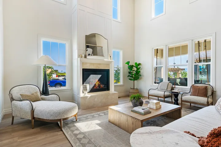 Living area with wood finished floors, a glass covered fireplace, and a high ceiling