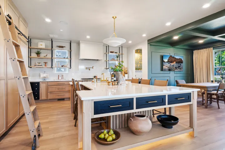 Kitchen with open shelves, two tone color scheme, hanging light fixtures, light wood finished floors, and a barn door