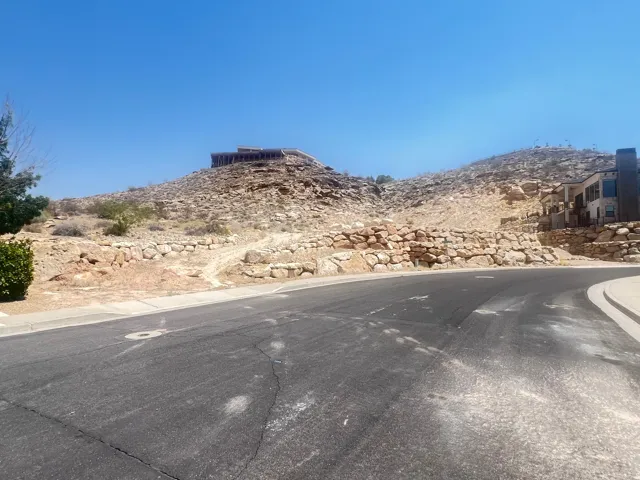View of asphalt road featuring curbs, a mountain view, and sidewalks