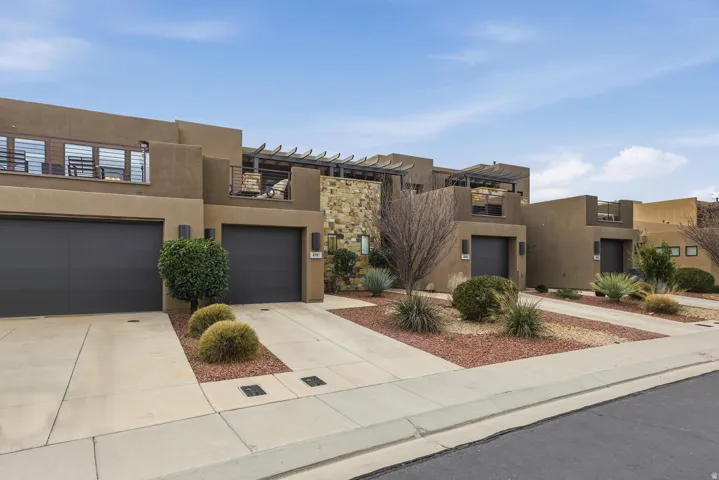 View of front of house featuring stucco siding, concrete driveway, and a garage