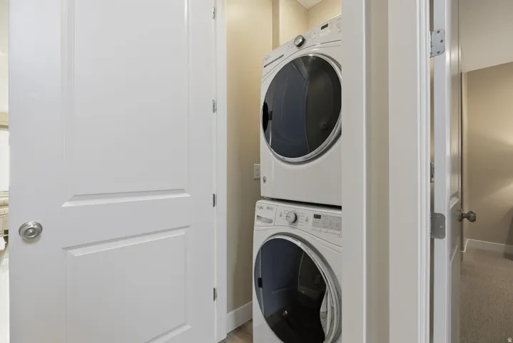 Laundry area featuring stacked washing machine and dryer and baseboards