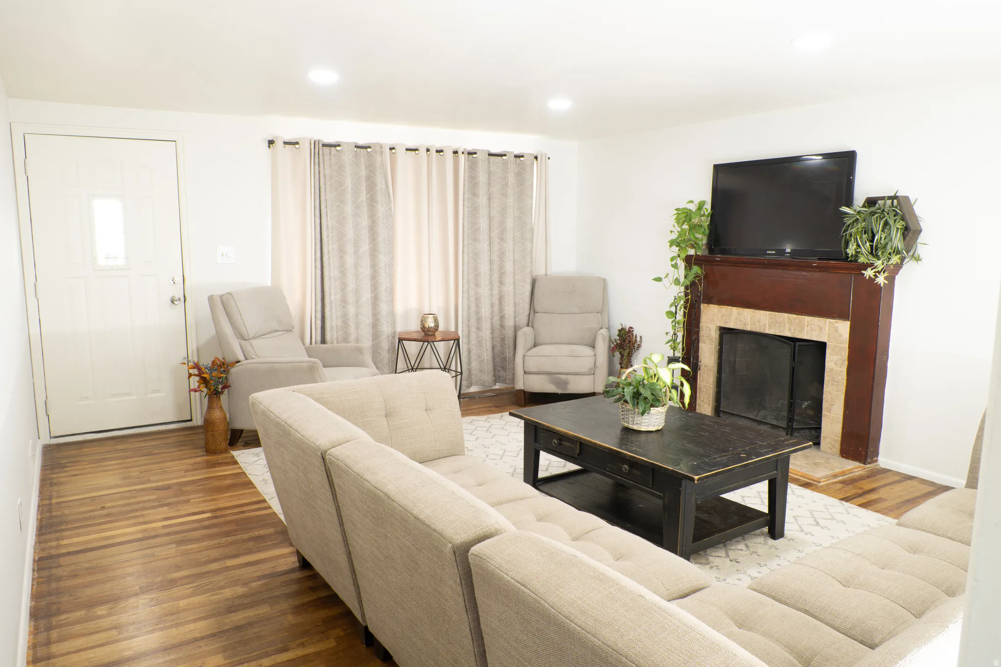 Living room with wood finished floors, a fireplace, and recessed lighting