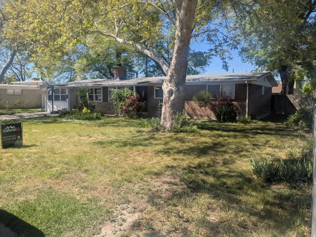 Back of house featuring a garage, brick siding, and a chimney