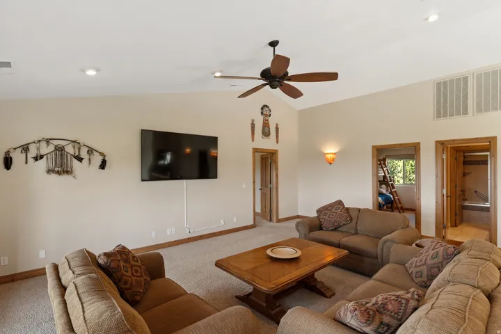 Carpeted living room with vaulted ceiling and a ceiling fan