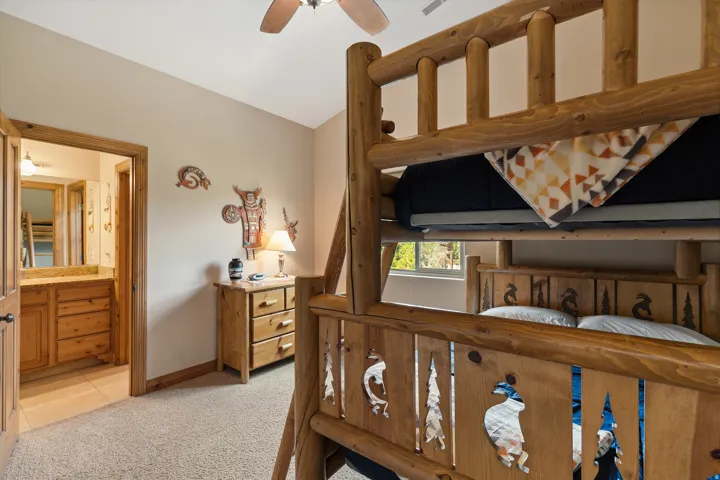 Bedroom featuring light colored carpet, lofted ceiling, connected bathroom, ceiling fan, and light tile patterned floors
