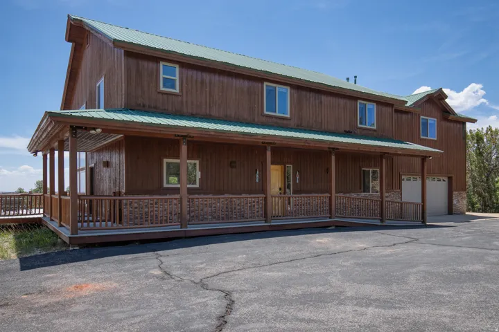 View of front of property with a metal roof, an attached garage, covered porch, and driveway