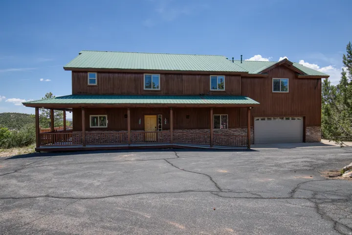 Chalet / cabin featuring an attached garage, a porch, a metal roof, and driveway