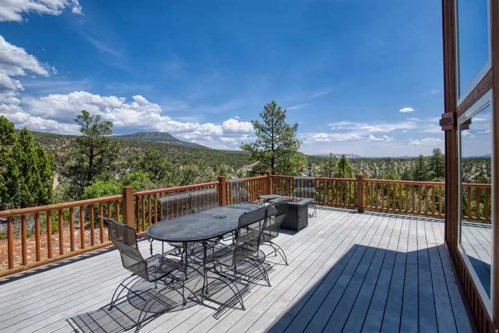 Wooden terrace with outdoor dining area, a wooded view, and a mountain view