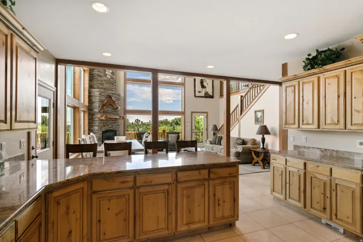 Kitchen with dark stone countertops, a kitchen breakfast bar, open floor plan, a fireplace, and light tile patterned floors