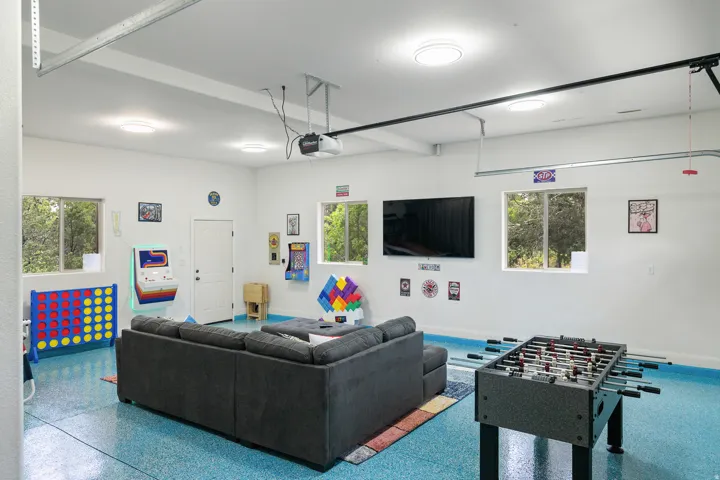 Living area featuring speckled floor, a garage, and beam ceiling