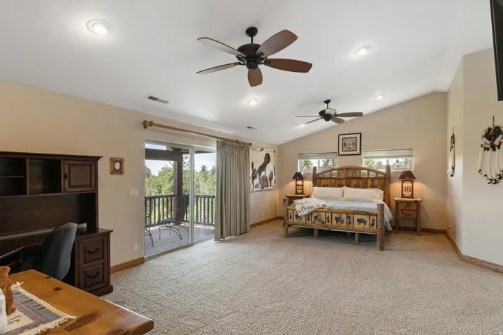 Bedroom with multiple windows, light colored carpet, access to outside, a ceiling fan, and vaulted ceiling
