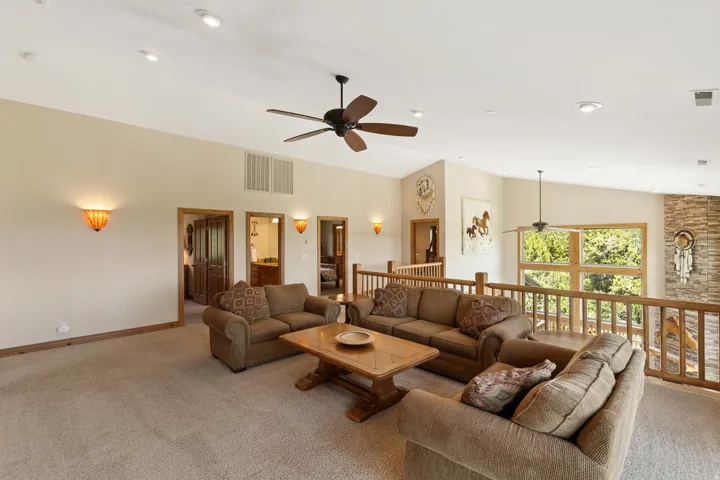 Carpeted living area featuring ceiling fan and vaulted ceiling